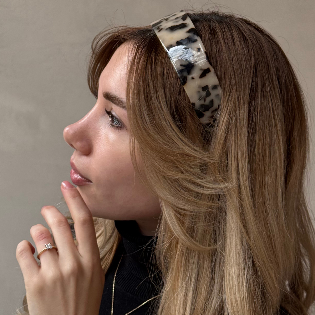 Woman wearing a leopard print headband against a neutral background