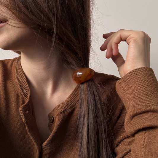 Person wearing a brown cardigan with a hair accessory, against a neutral background