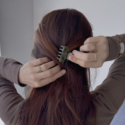 Person styling their hair with a hair clip against a neutral background
