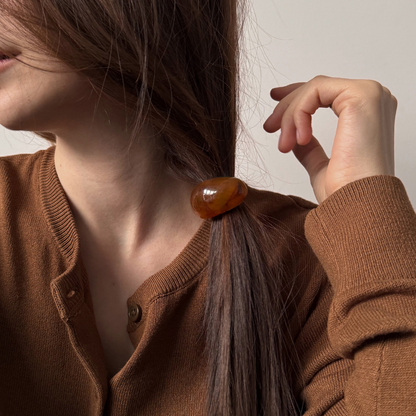 Person wearing a brown cardigan with a hair accessory, against a neutral background