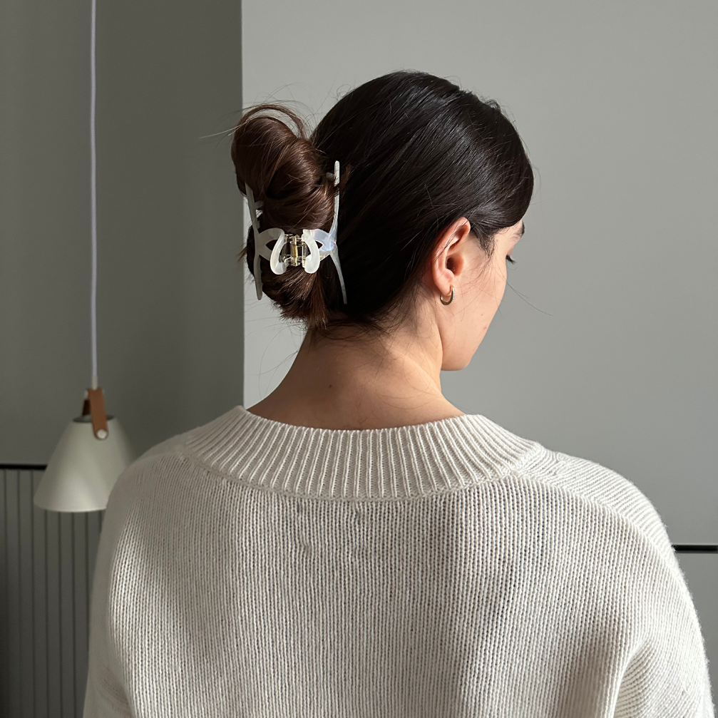 Woman with a hair clip in her bun against a gray wall