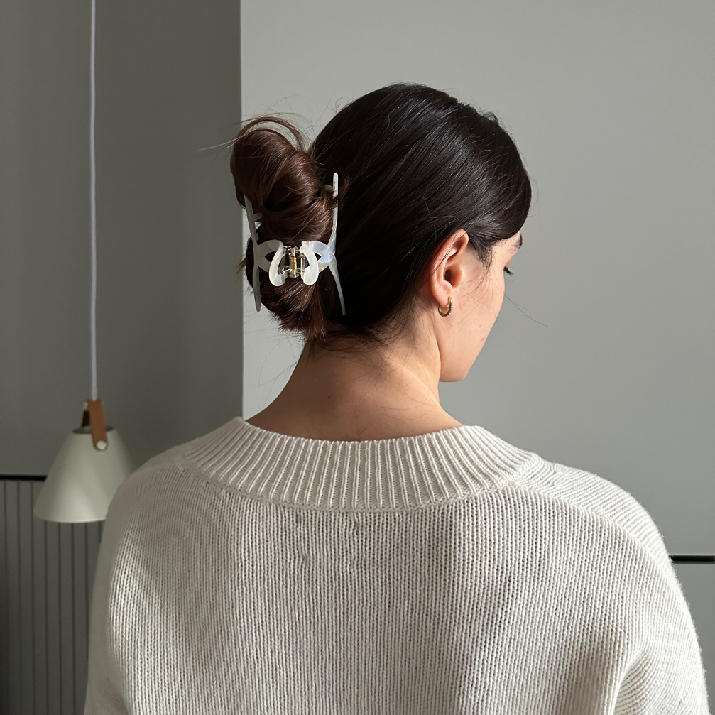 Woman with a hair clip in her bun against a gray wall