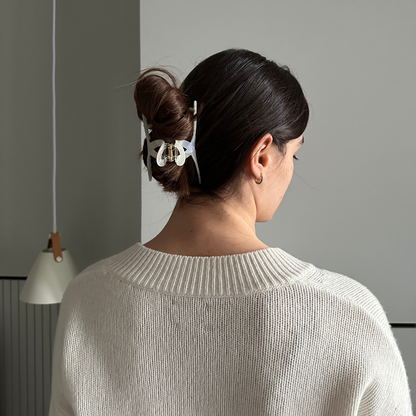 Woman with a hair clip in her bun against a gray wall