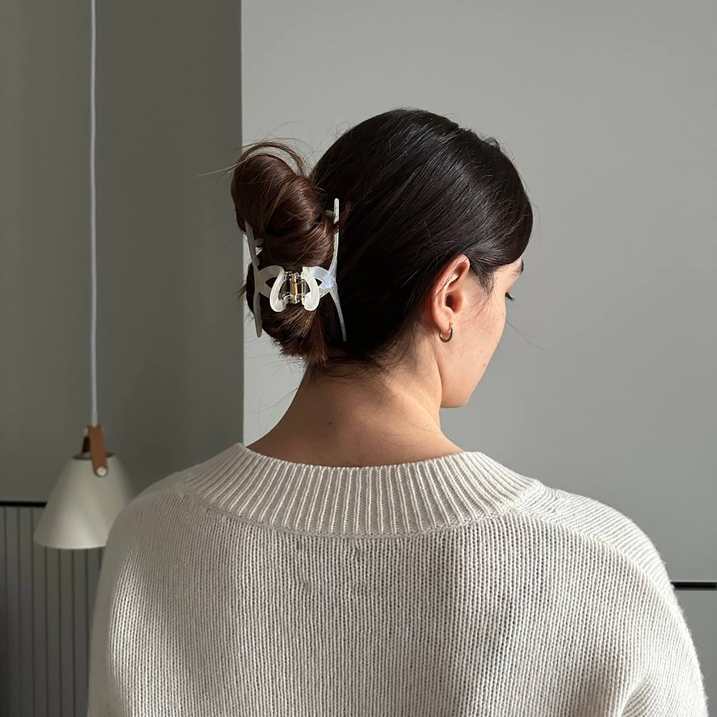 Woman with a hair clip in her bun against a gray wall