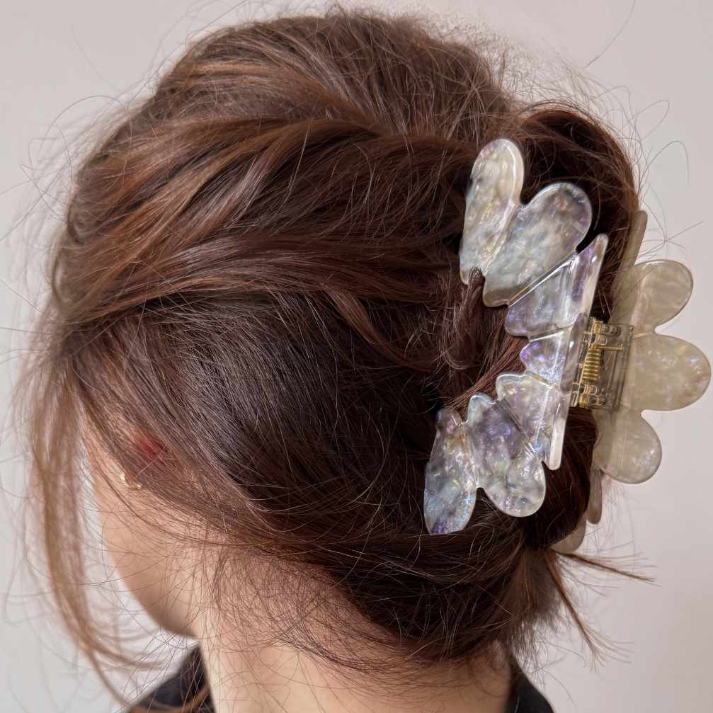 Person with decorative hair clip in their hair against a neutral background