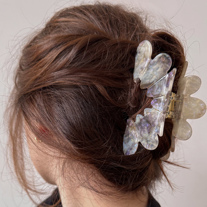 Person with decorative hair clip in their hair against a neutral background
