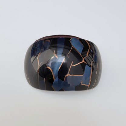 Black and blue hair tie with a cracked design on a white background