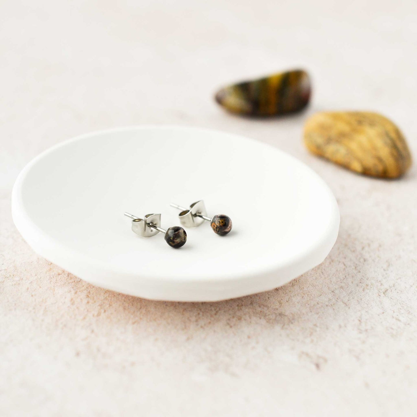 Tiny dark gemstone stud earrings in trinket dish