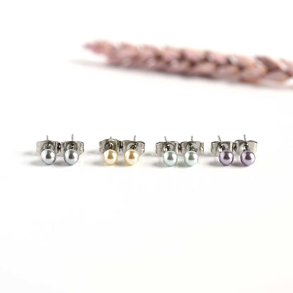 Four pairs of pastel faux pearl stud earrings on white background