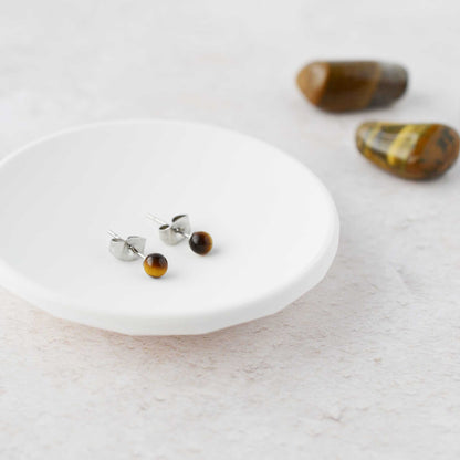 Tiny Tiger's Eye gemstone stud earrings in white trinket dish.