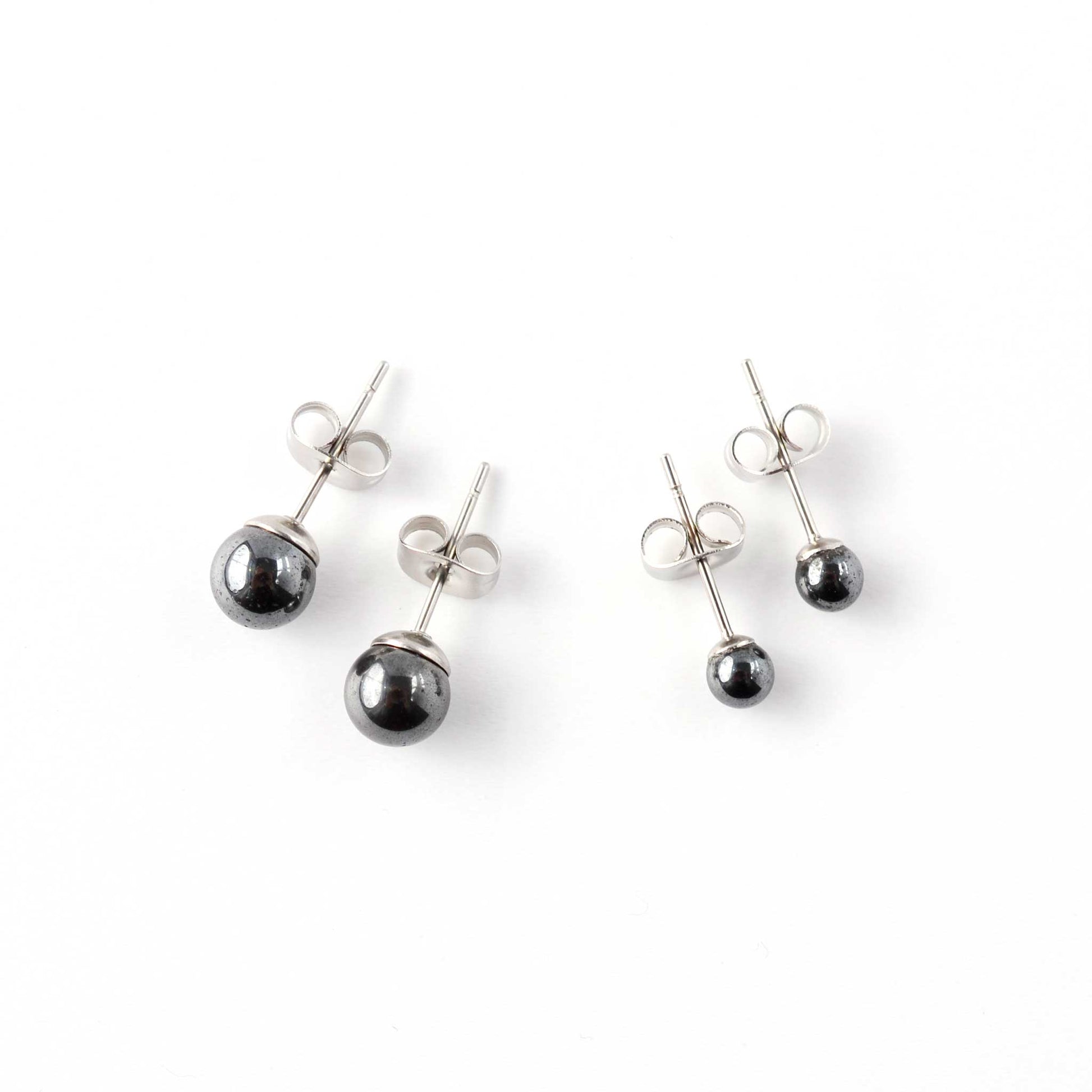 Small and large Hematite stud earrings laying on white background.