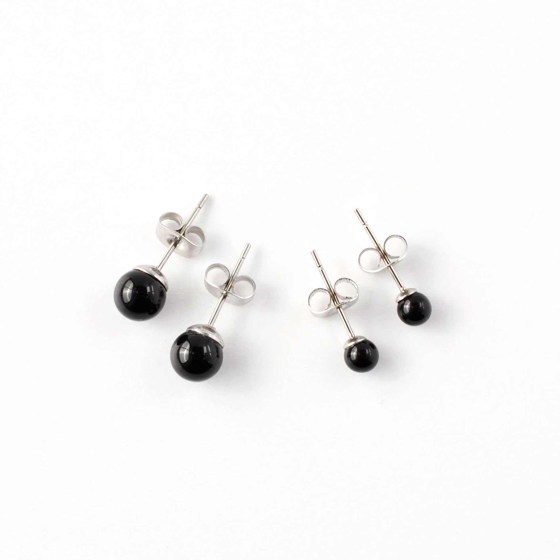 Small and large Onyx stud earrings laying on white background.