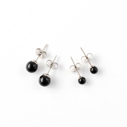 Small and large Onyx stud earrings laying on white background.