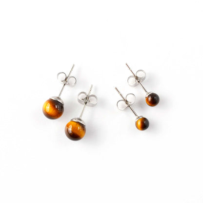 Small and large Tiger's eye stud earrings laying on a white background.
