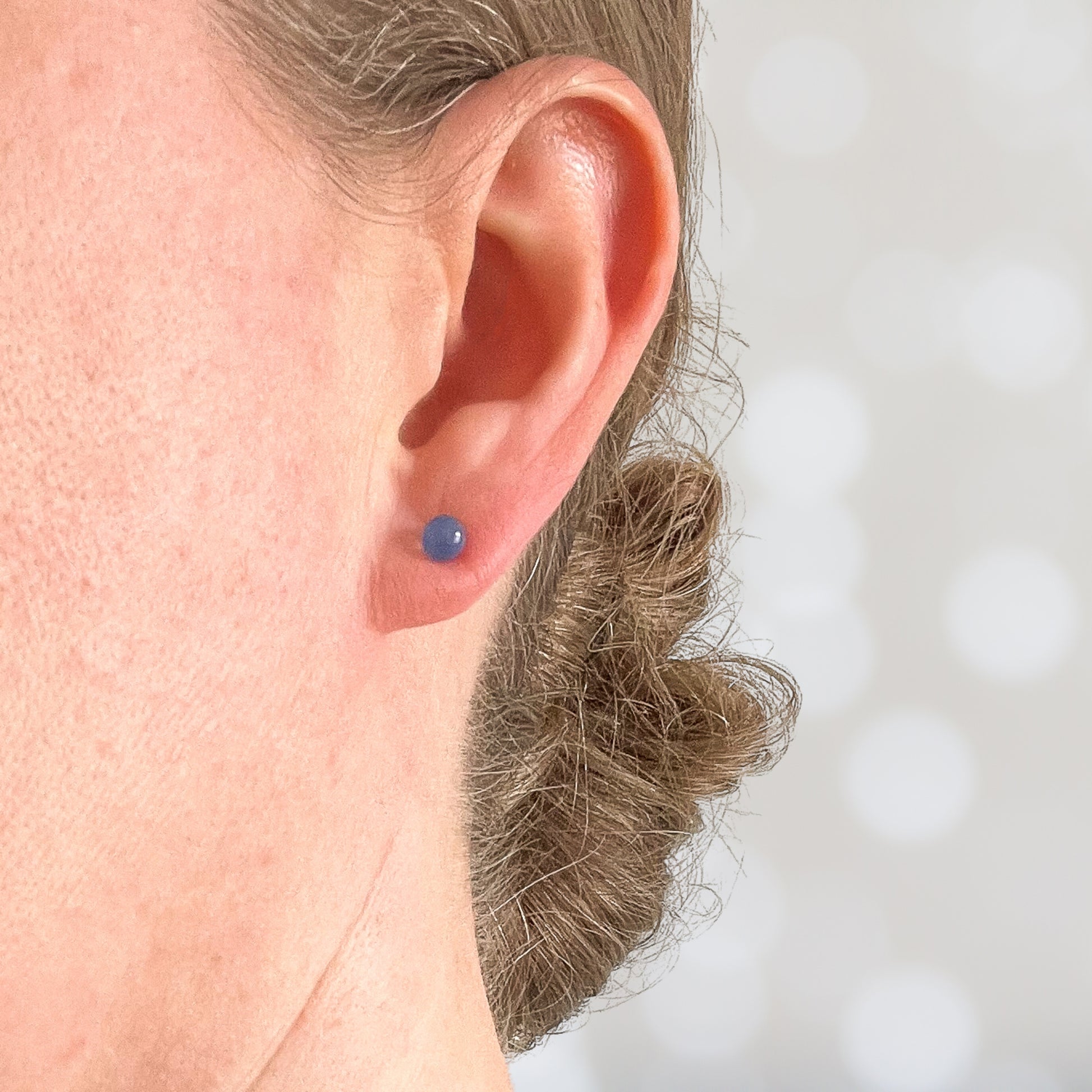 Woman wearing tiny blue stone earring in earlobe