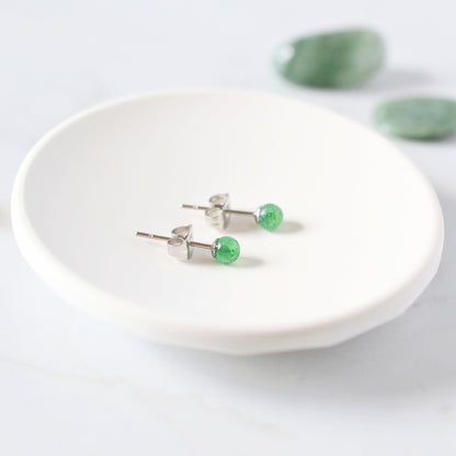 Green stone earrings on a white trinket dish with a light background