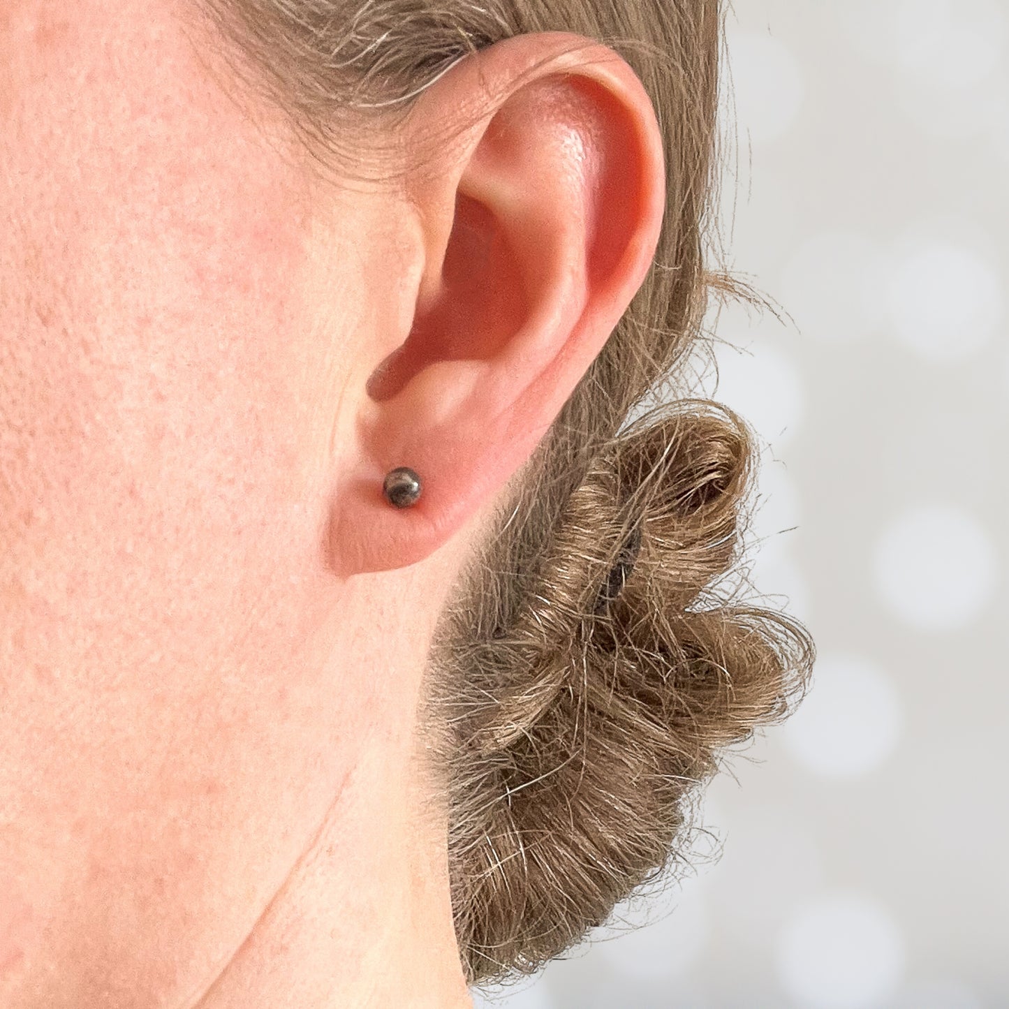 Woman wearing tiny natural gemstone earring in earlobe