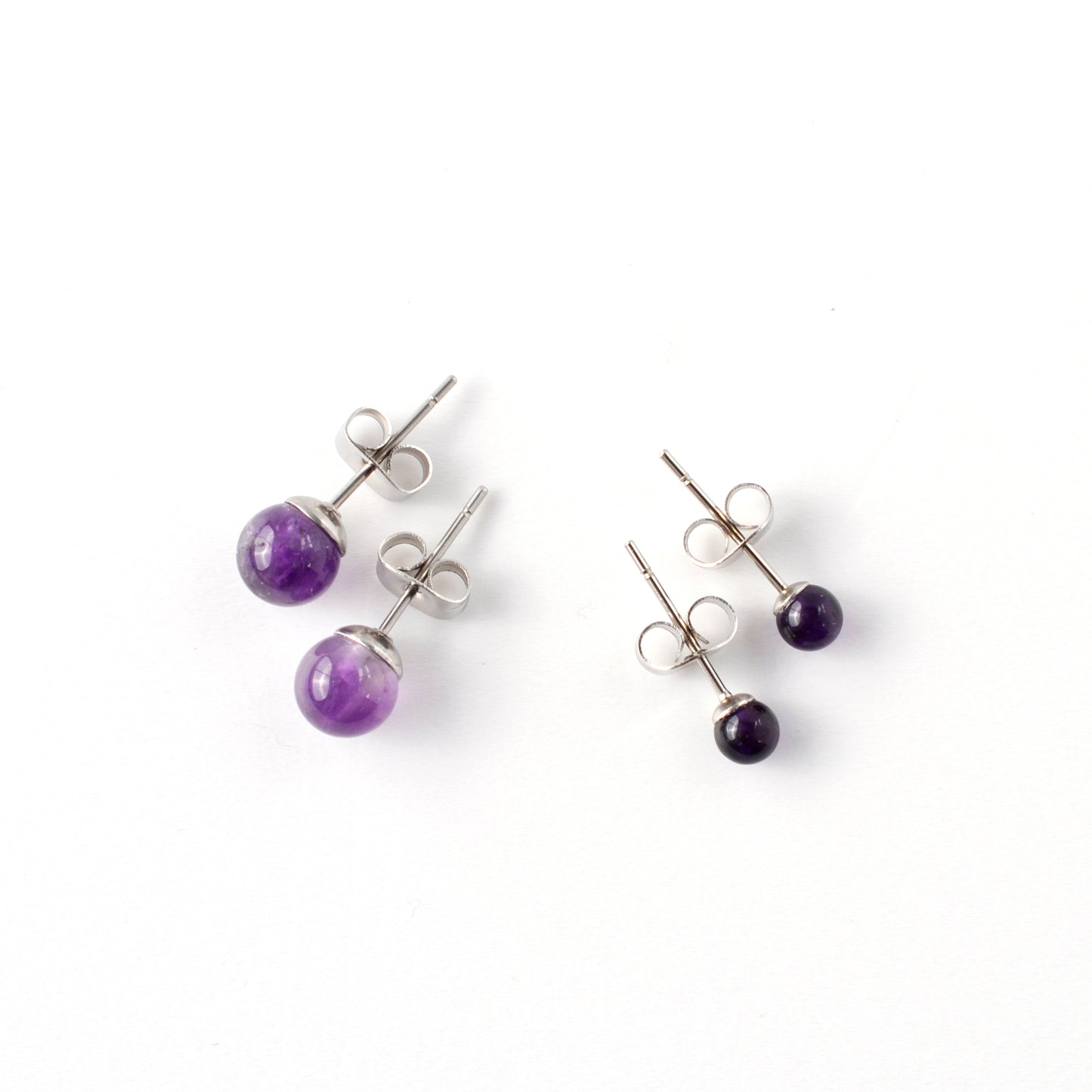 Small & Large Amethyst stud earrings laying on a white background.