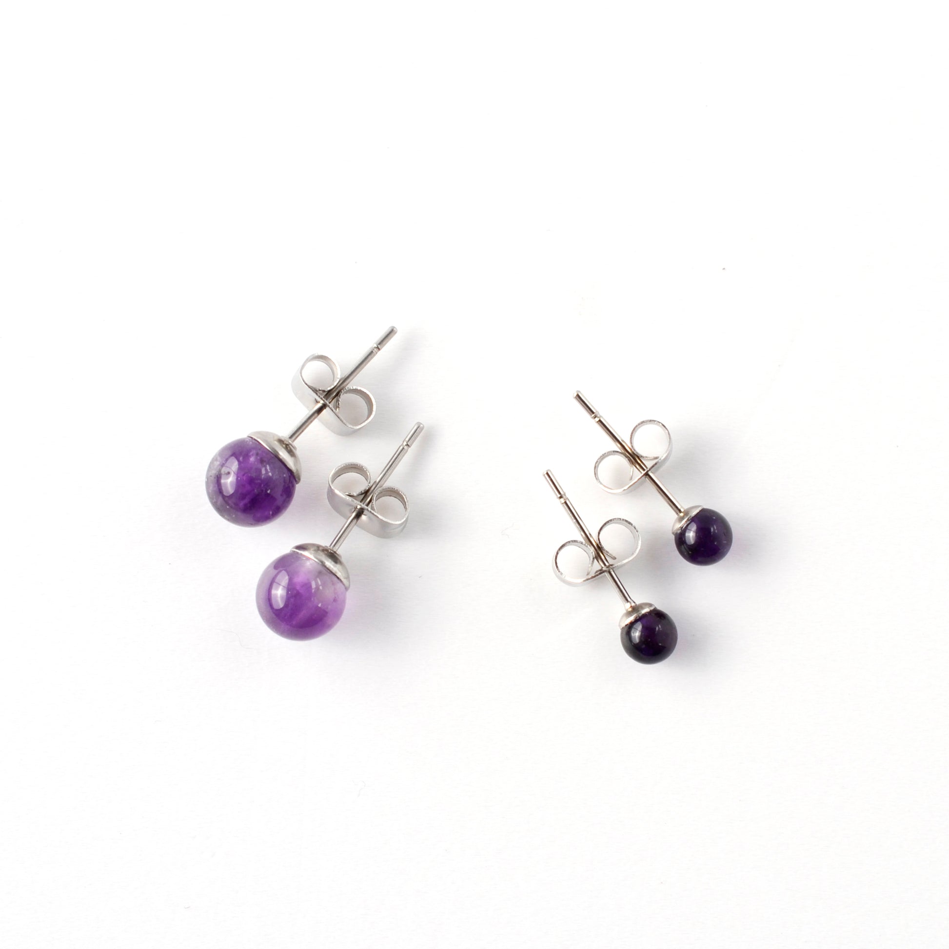 Small & Large Amethyst stud earrings laying on a white background.