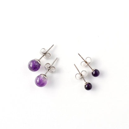 Small & Large Amethyst stud earrings laying on a white background.