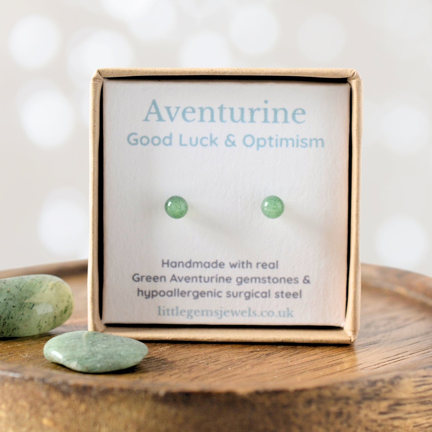 Box of green aventurine earrings with stones on a wooden surface