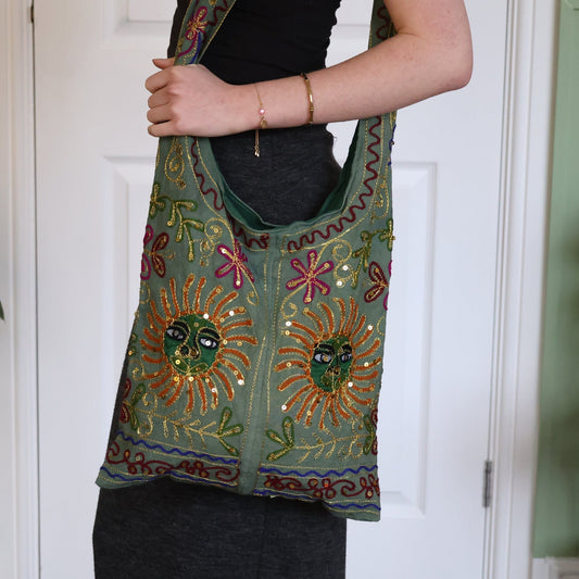 Person holding a colorful embroidered bag in front of a white door.