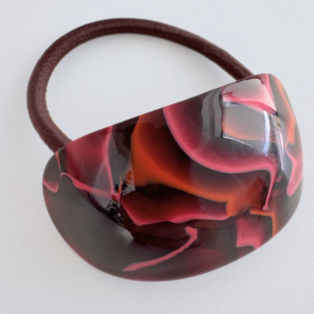 Marbled hair tie with red and black design on a white background