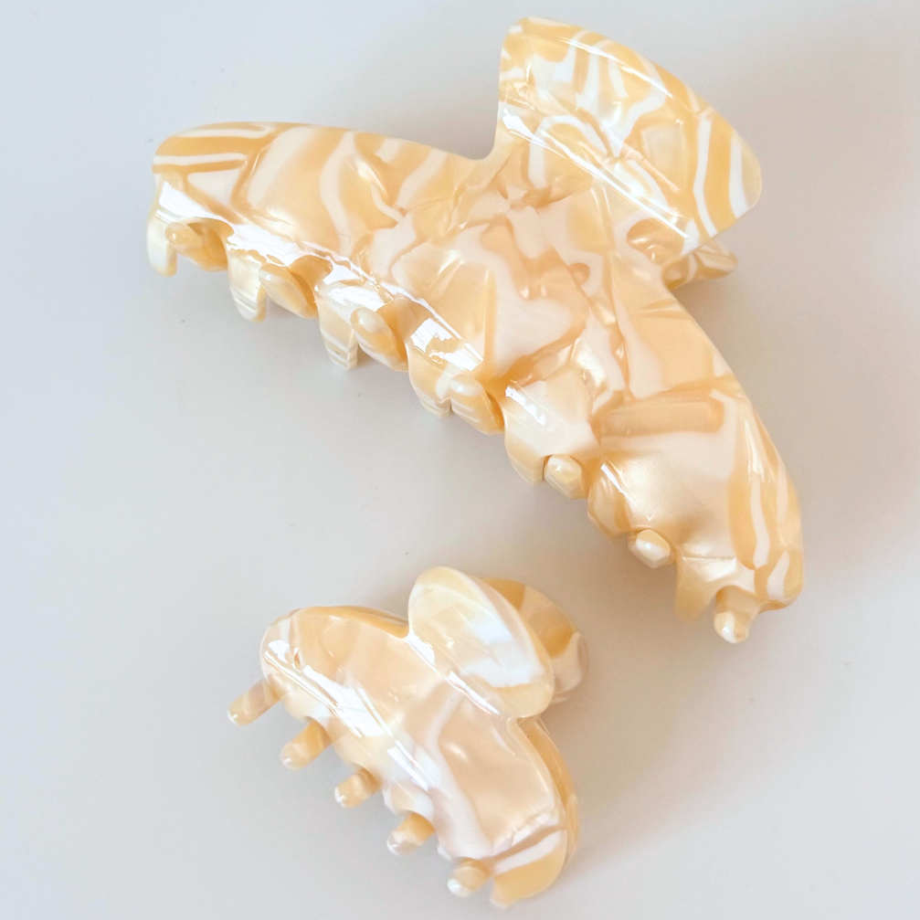 Decorative hair clips with a beige pattern on a light gray background