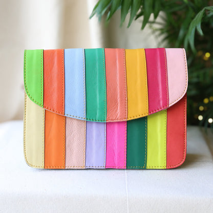 Colorful striped handbag on a white surface with a blurred plant in the background