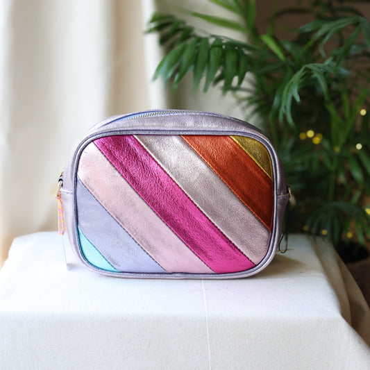 Multicolored striped pouch on a white surface with a plant in the background