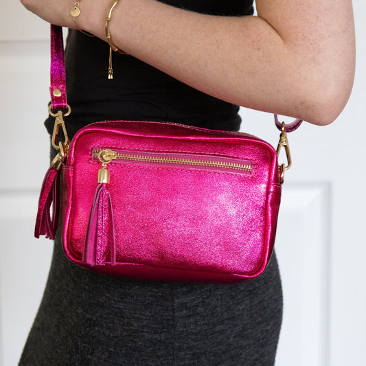 Person holding a pink metallic handbag with gold accents