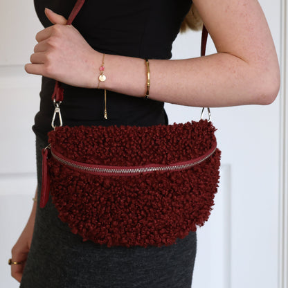 Person holding a textured red handbag against a white background