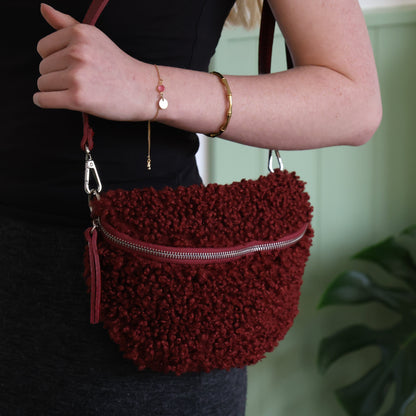 Red textured handbag held by a person with a blurred background