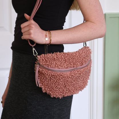 Person holding a pink textured handbag with a blurred background