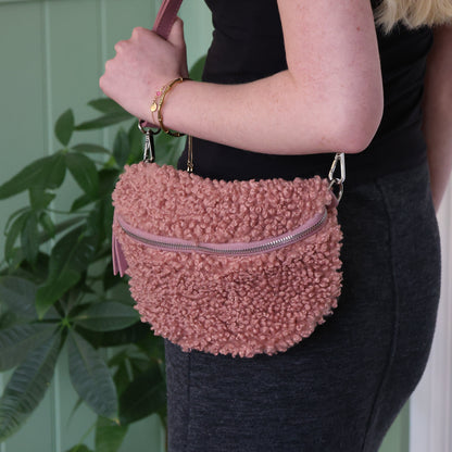 Person holding a pink textured handbag with a plant in the background