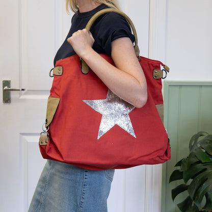 Person holding a red bag with a silver star design indoors.