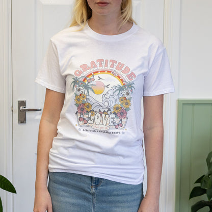 Person wearing a white t-shirt with a graphic design in a room with green plants.