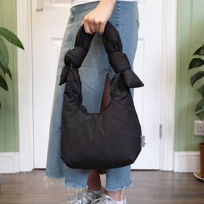 Person holding a black bag in a room with plants