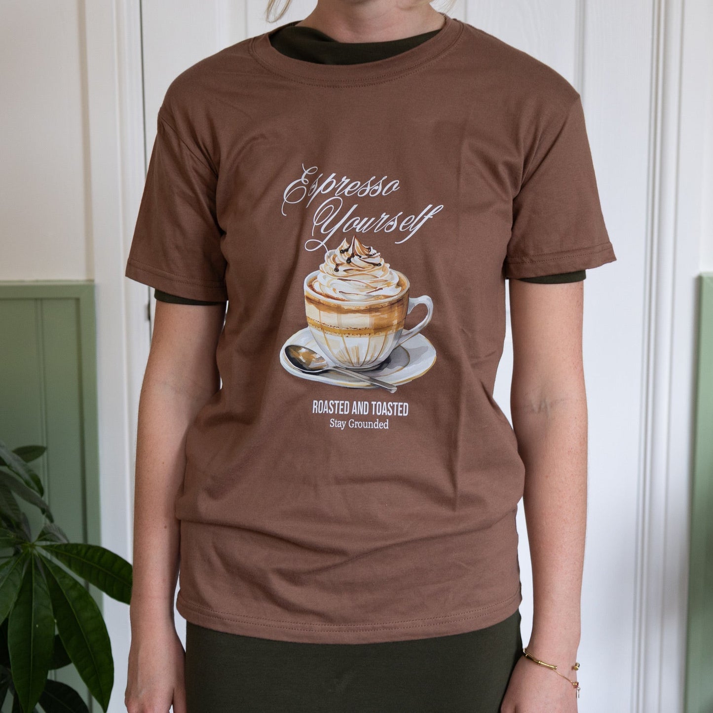 Person wearing a brown t-shirt with a coffee-themed graphic and text.