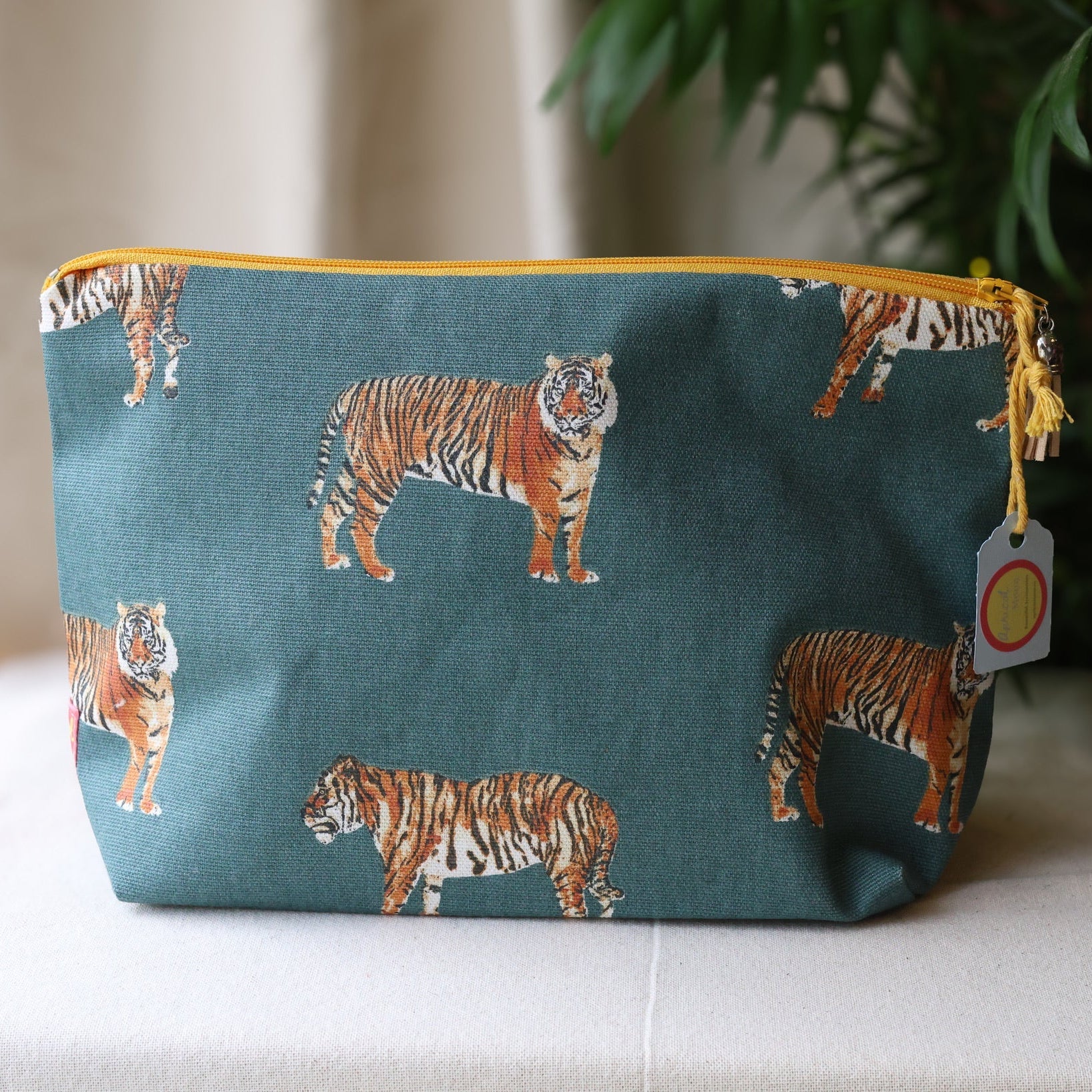 Teal pouch with tiger pattern on a white surface with a plant in the background