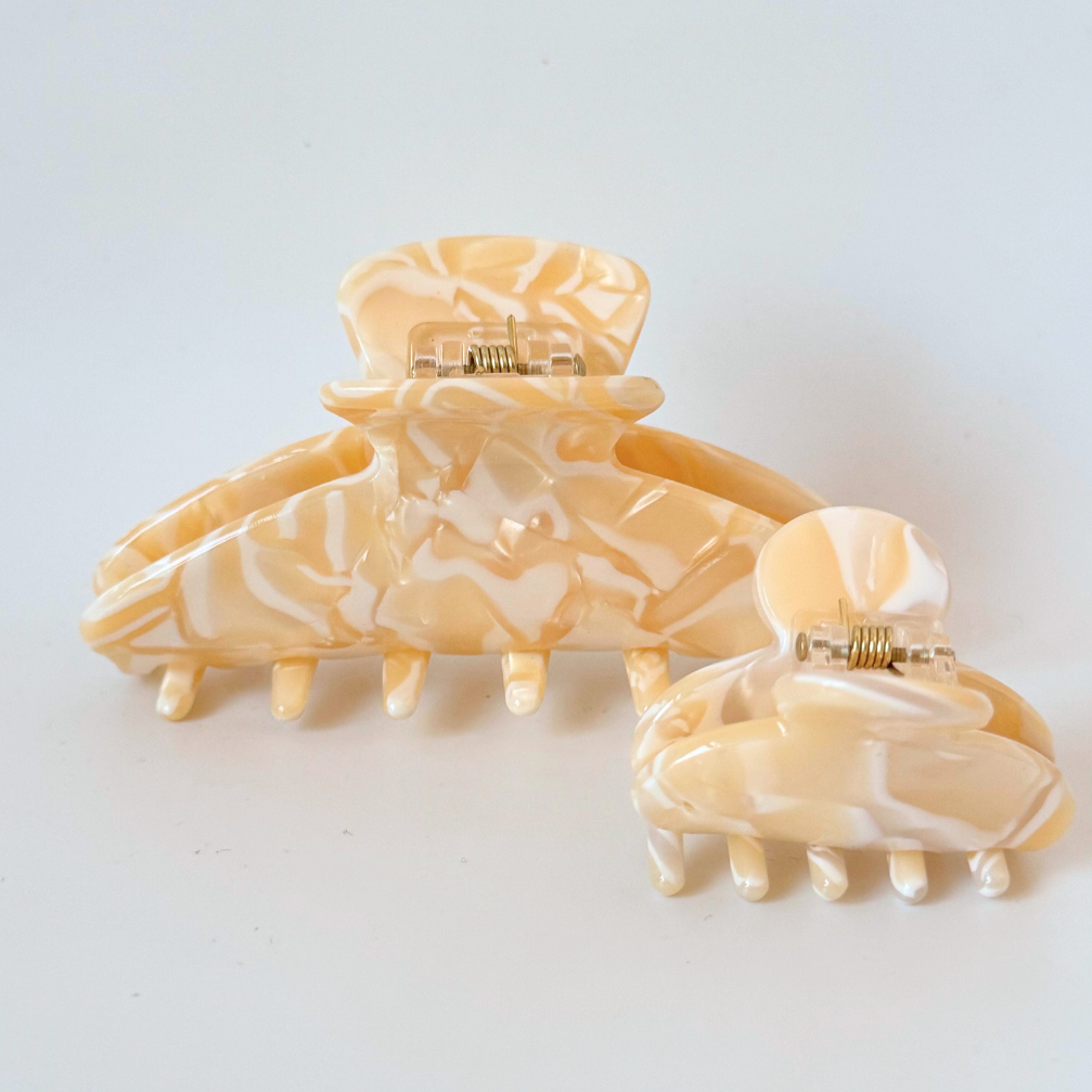 Two marbled hair clips on a light gray background