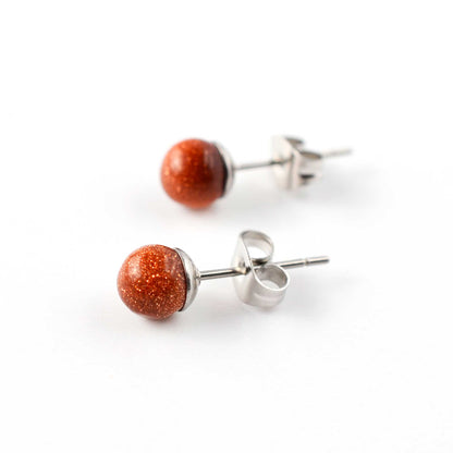 Side view of Goldstone round ball stud earrings on white background.