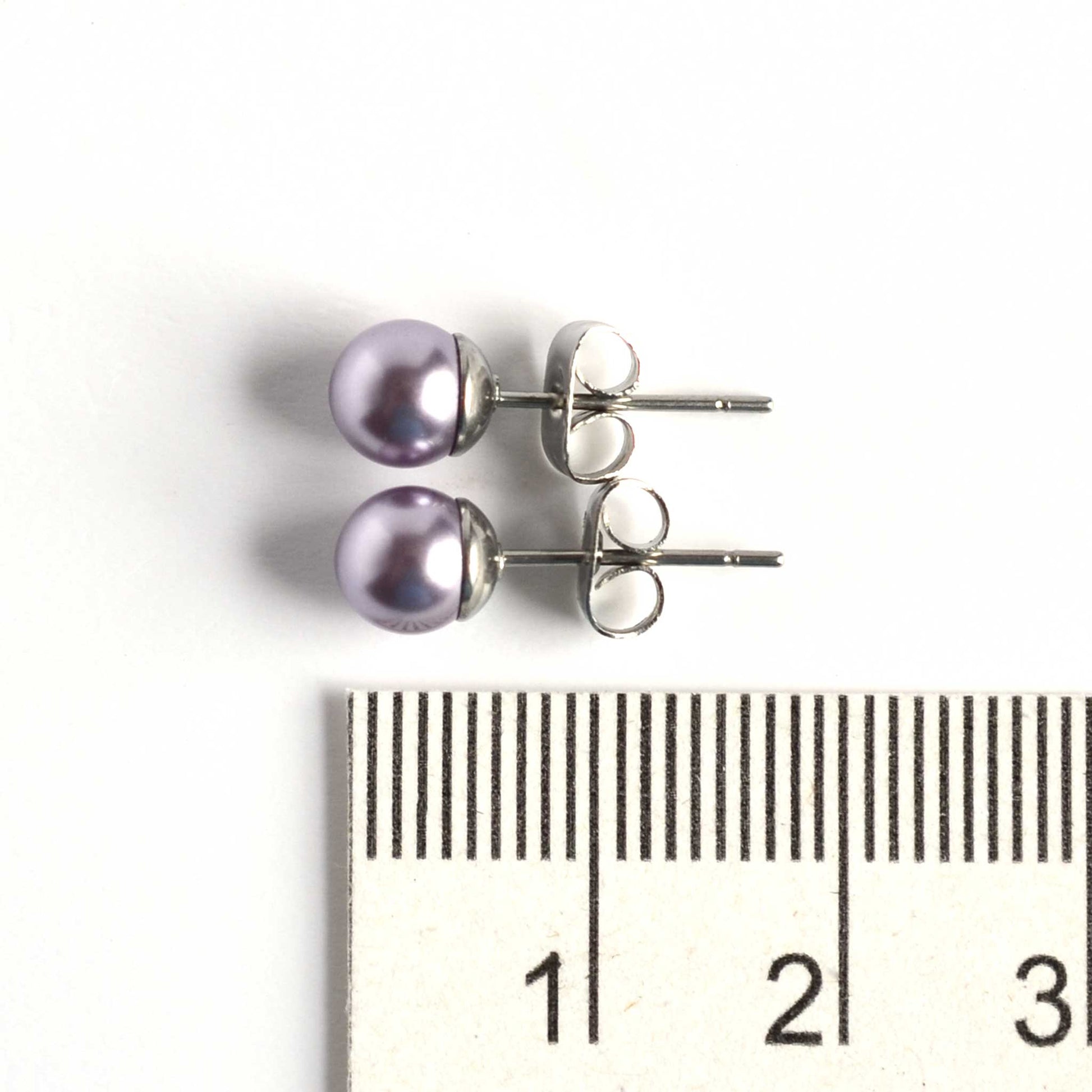 6mm light purple faux pearl stud earrings next to ruler