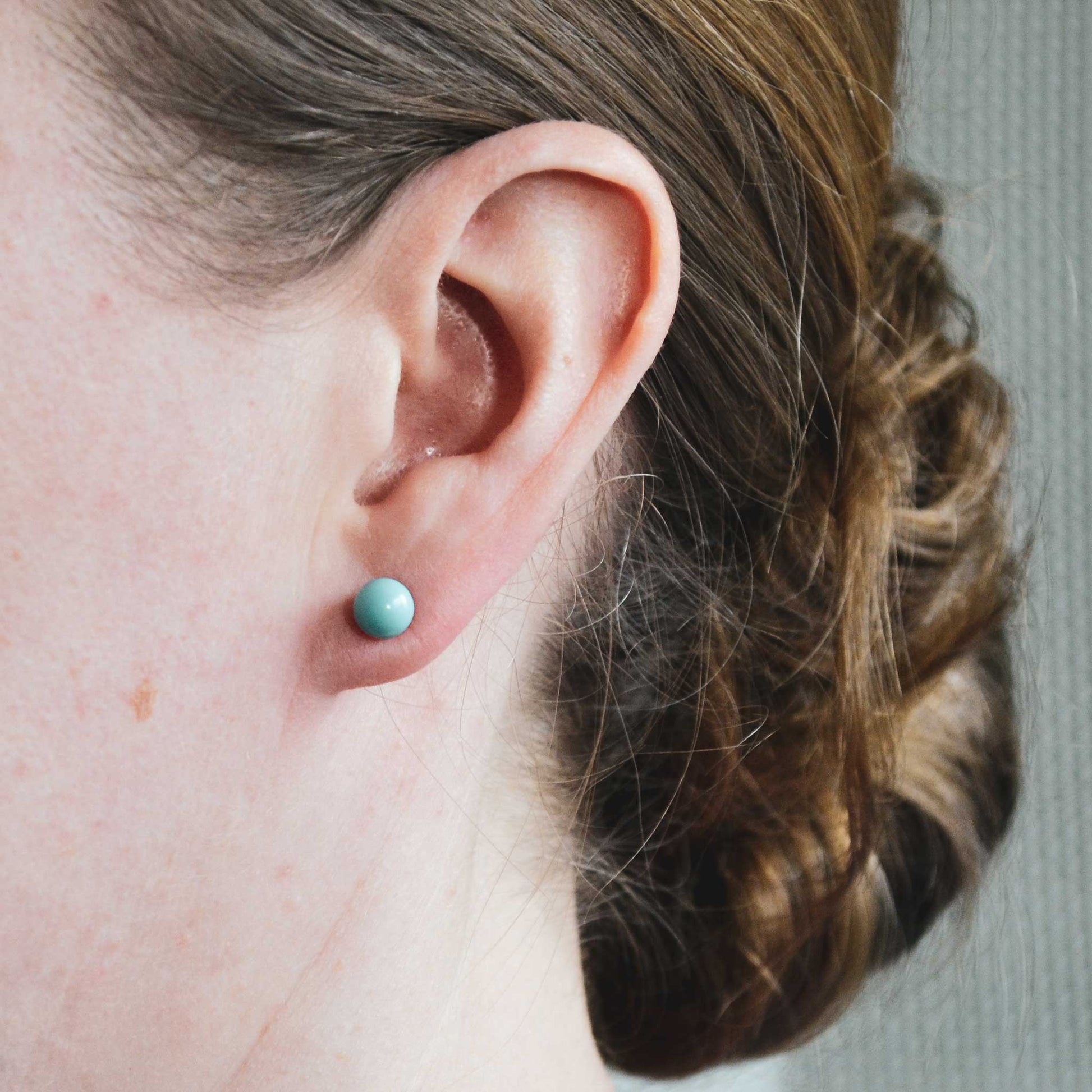 Woman wearing simple Turquoise ball stud earring in earlobe