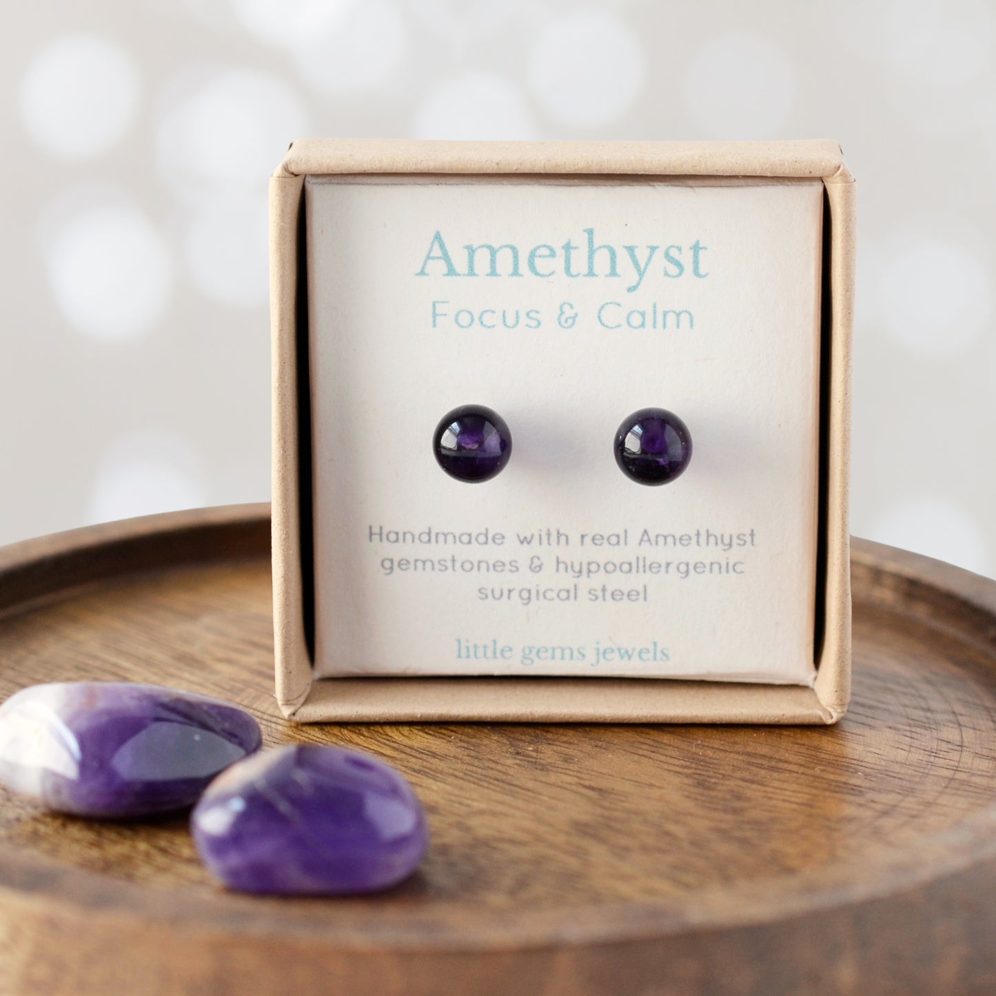 Amethyst earrings in a display box on a wooden surface