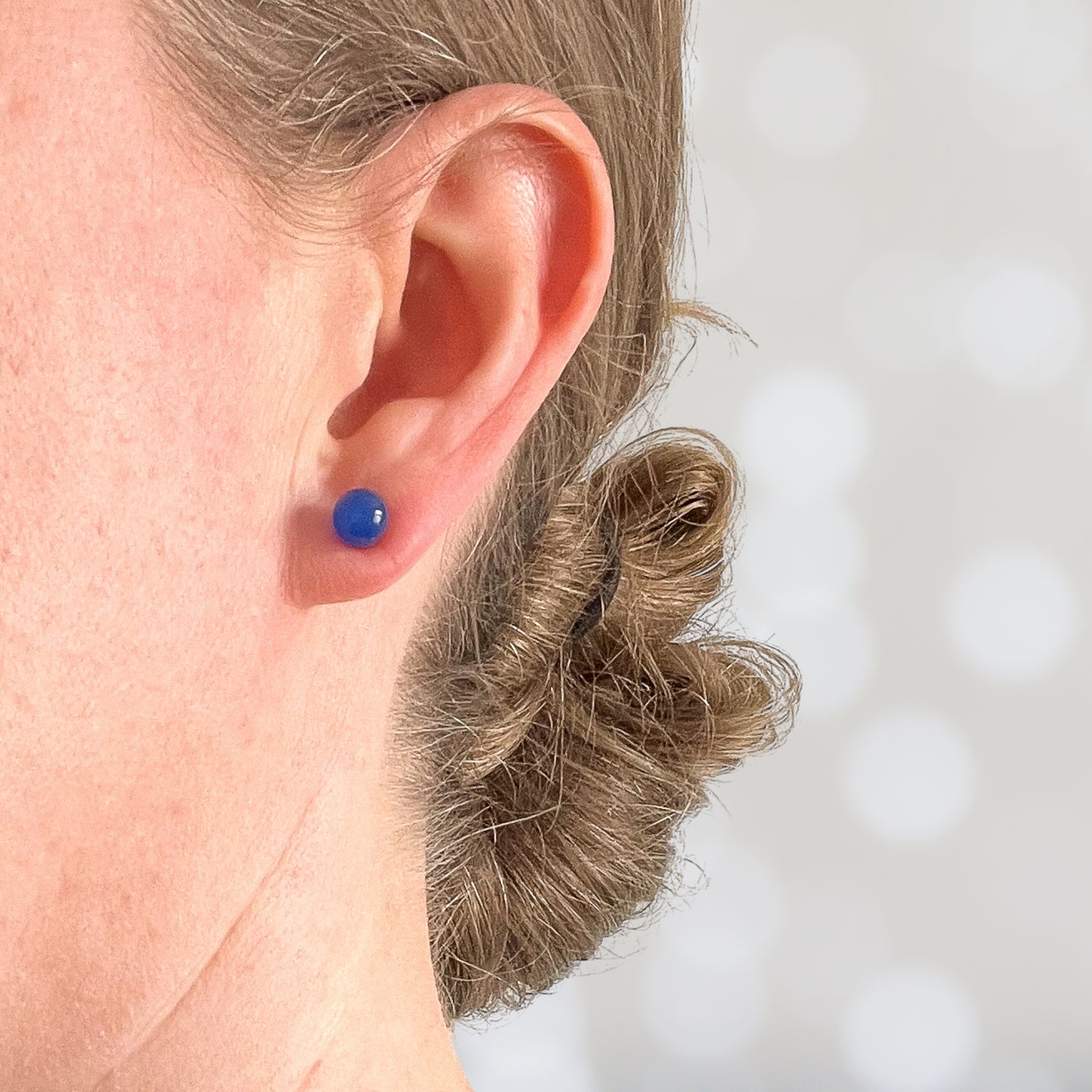 Woman wearing blue gemstone stud earring in earlobe