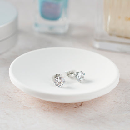 CZ Stud earrings on white trinket dish with soft focus background.