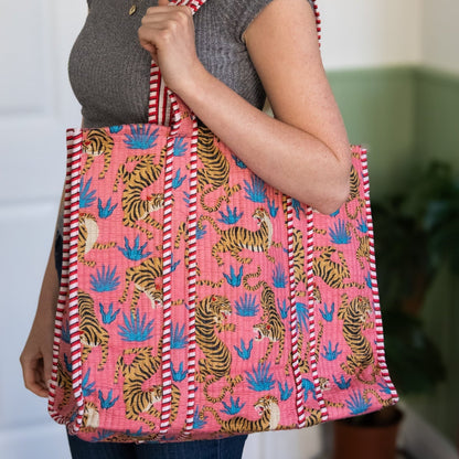 Person holding a pink tote bag with tiger pattern