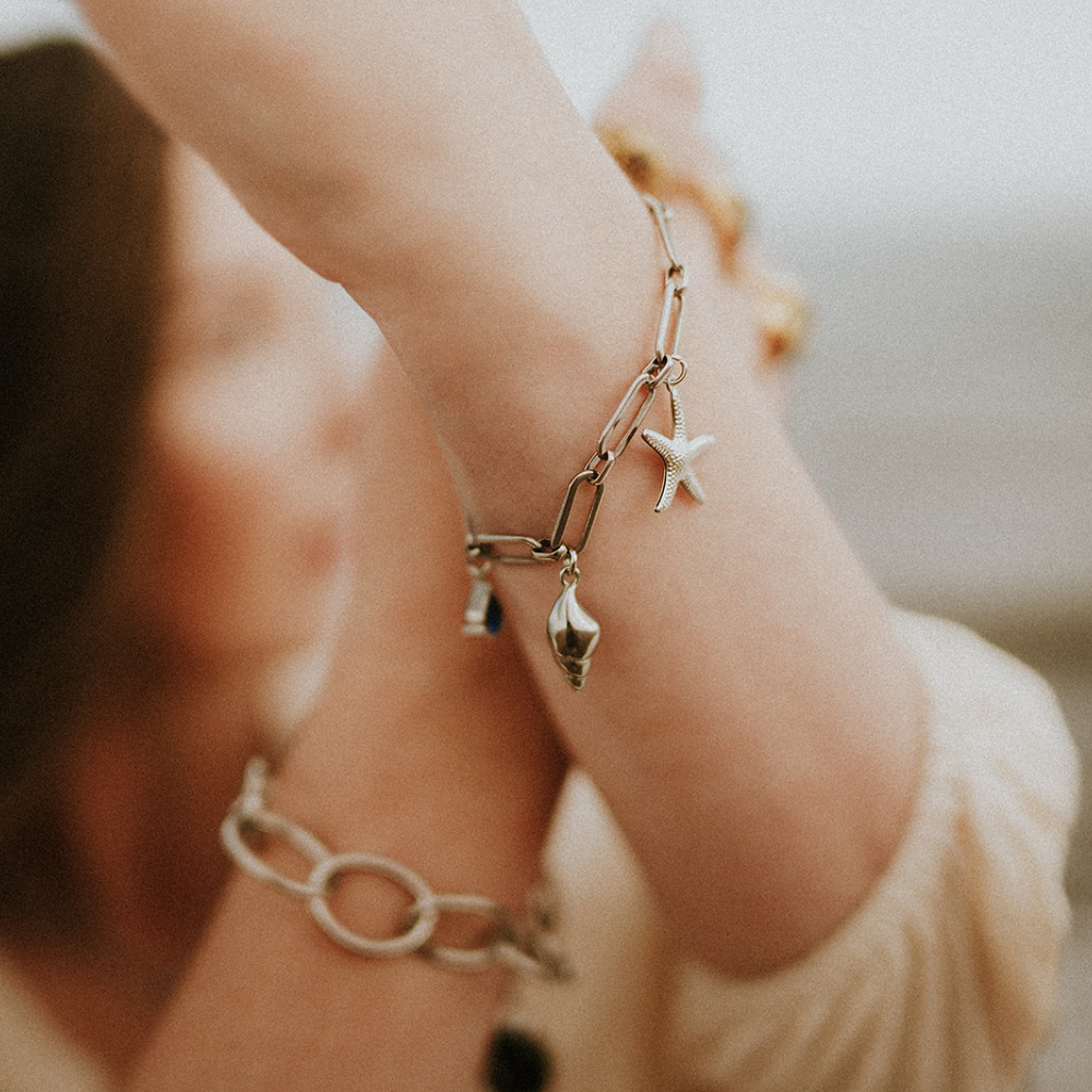 Close-up of a woman's arm wearing a bracelet with star charm against a blurred background