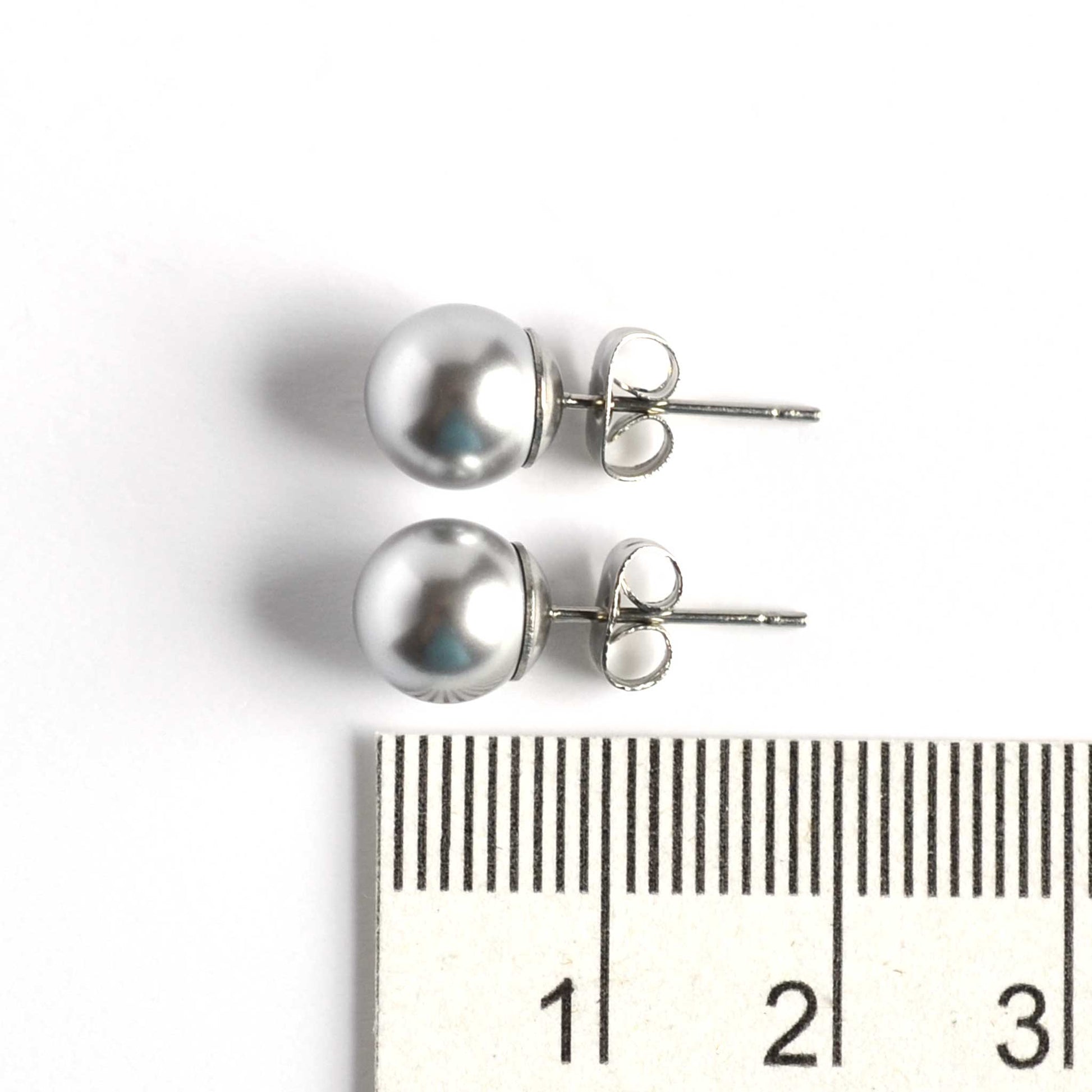 8mm light grey faux pearl stud earrings next to ruler